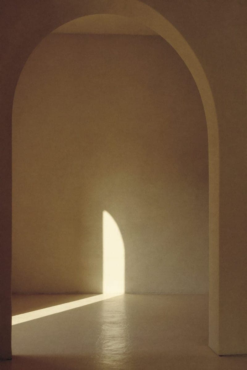 A plaster archway with a shaft of low sunlight crossing the floor