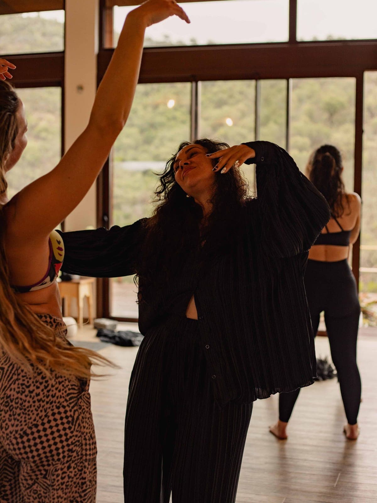 Camila Mello leading movement with the group in the retreat room, head tipped back